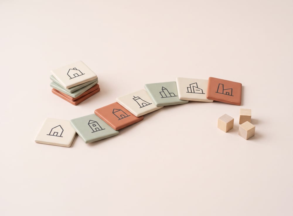 Cream and terracotta architectural game tiles laid out in a curve with wooden marker cubes.