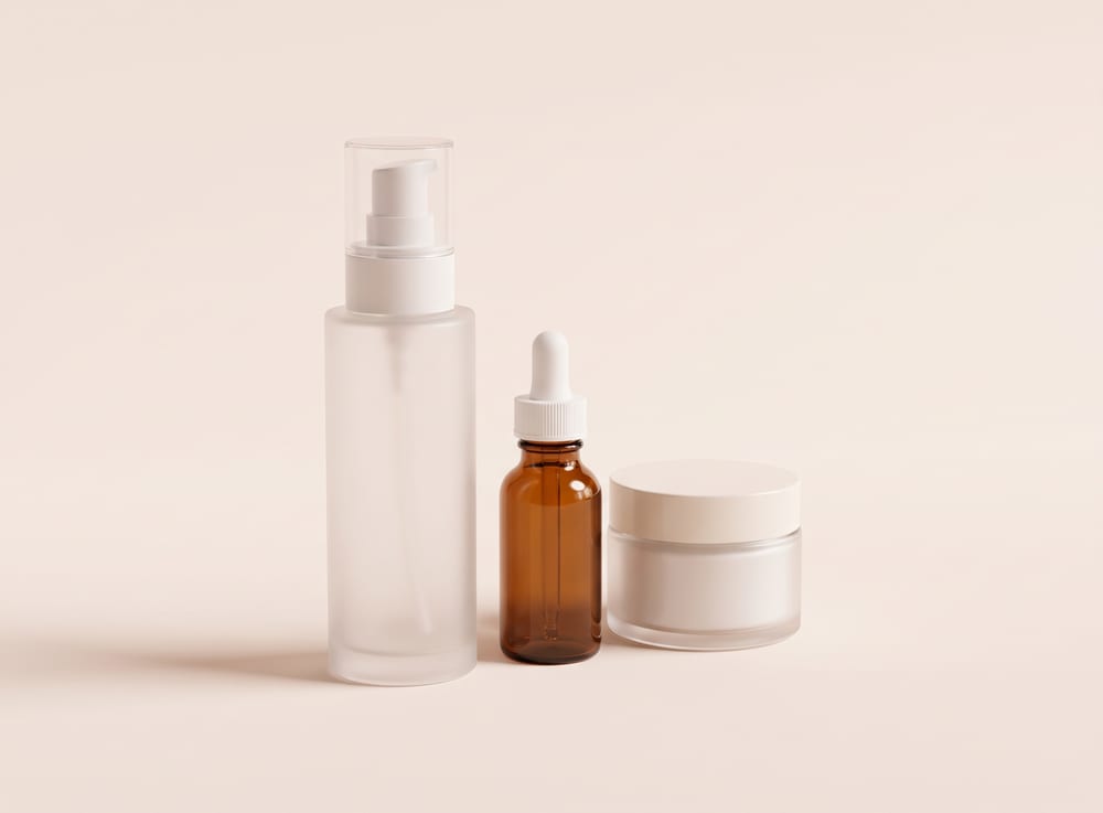 A frosted pump bottle, an amber dropper bottle and a cream jar grouped together.